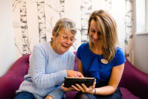 Pure Dental receptionist helping patient find information on tablet device.